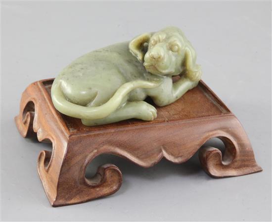 A Chinese green jade figure of a recumbent dog, length 12.5cm excl. wood stand